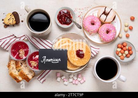 Tisch mit verschiedenen amerikanischen Keksen, Donuts, Pfannkuchen und Kaffeetassen auf weißem Hintergrund. Draufsicht. Stockfoto