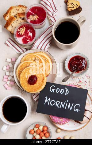 Tisch mit verschiedenen amerikanischen Keksen, Donuts, Pfannkuchen und Kaffeetassen auf weißem Hintergrund. Draufsicht. Stockfoto
