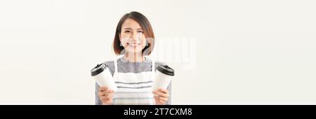 Freundlich lächelnde junge asiatische Frau in Schürze, die Kaffee Tee heiße Getränketassen hält Stockfoto