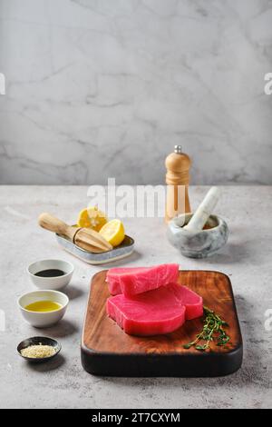 Rohes Ahi Thunfischsteak auf Schneidebrett mit Gewürzen Stockfoto