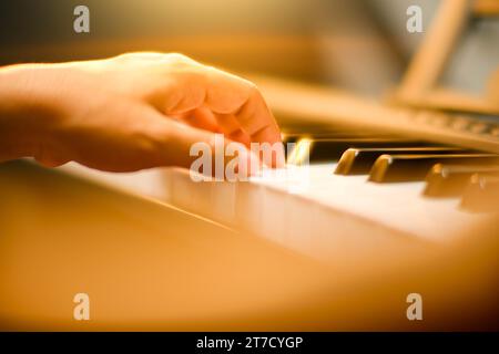 Nahaufnahme der Hand eines kleinen Schülers, der Klavier spielt. Glückliches junges asiatisches Mädchen, das Klavier lernt und übt. Selektiver Fokus. Stockfoto