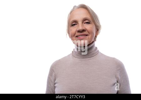 Oma mit grauen Haaren, die süß lächelnd im Studio mit weißem Hintergrund sind Stockfoto