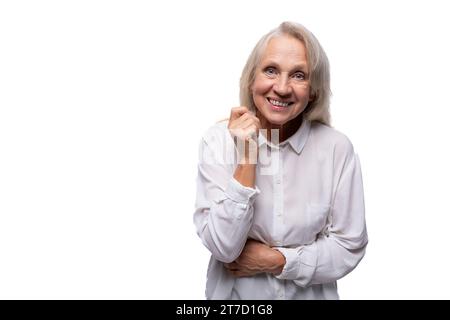 65 Jahre alte glückliche europäische reife Frau, die Hemd auf weißem Hintergrund trägt Stockfoto