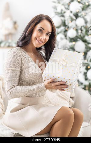 Die lächelnde Frau zeigt ihr Weihnachtsgeschenk vor die Kamera, alle glücklich mit dem Geschenk. Stockfoto