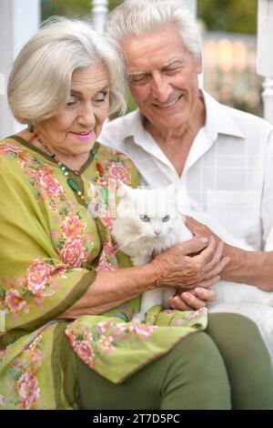 Ein älteres Paar hält im Sommer eine Katze in den Armen Stockfoto