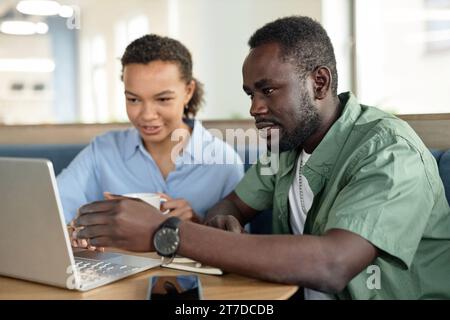 Junge Kollegen, die während der Besprechung im Café gemeinsam am Laptop arbeiten Stockfoto
