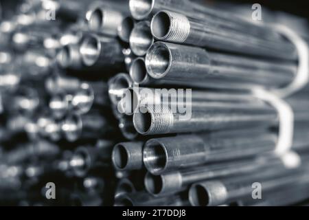 Metallrohre Verbindungsrohre. Zylindrisches Stahlrohr in valider Größe in den Regalen für Baumaschinen gestapelt. Stockfoto