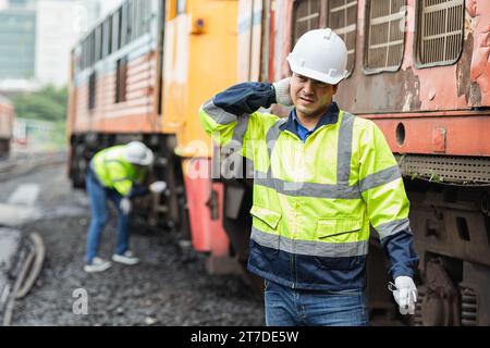 Ingenieurarbeiter müde von harter Arbeit im Freien bei heißem Wetter mit alten männlichen Servicemitarbeitern im Dieselzug Stockfoto