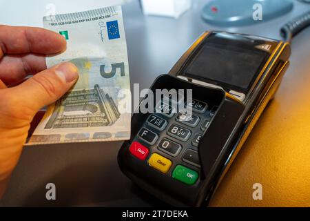 Augsburg, Bayern, Deutschland - 21. Juni 2023: Hand mit einem 5-Euro-Schein an einen EC-Kartenleser. Symbolbild der Bargeld- und Kartenzahlung *** Hand halten 5-Euro Schein an ein EC-Kartenlesegerät. Symbolbild Bargeld und Kartenzahlung Credit: Imago/Alamy Live News Stockfoto