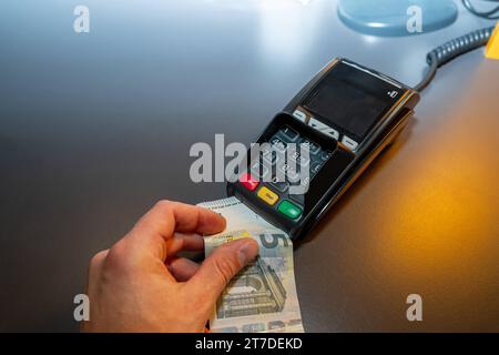 Augsburg, Bayern, Deutschland - 21. Juni 2023: Hand mit einem 5-Euro-Schein an einen EC-Kartenleser. Symbolbild der Bargeld- und Kartenzahlung *** Hand halten 5-Euro Schein an ein EC-Kartenlesegerät. Symbolbild Bargeld und Kartenzahlung Credit: Imago/Alamy Live News Stockfoto