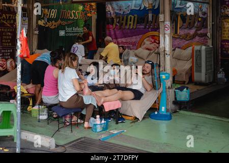 Bangkok, Thailand. November 2023. Touristen werden bei einer Fußmassage auf dem Wochenendmarkt in Chatuchak beobachtet. Der Chatuchak Weekend Market oder JJ Market ist einer der größten Outdoor Märkte der Welt und der größte Markt in Thailand für Einheimische und Touristen. Quelle: SOPA Images Limited/Alamy Live News Stockfoto