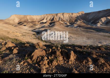 Das erste Licht des Sonnenaufgangs wirft ein goldenes Licht auf die bergige, trockene, karge Landschaft der Judäischen Wüste Israels. Stockfoto