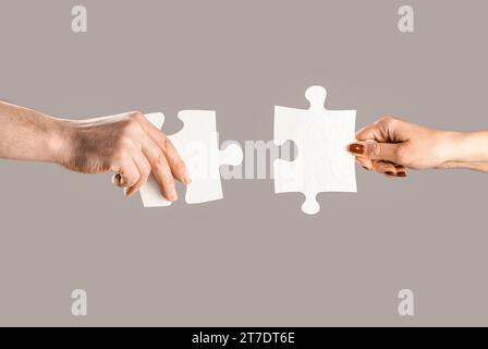 Puzzles. Mann und Frau halten ein Puzzle in der Hand. Geschäftslösungen, Erfolg und Strategiekonzept. Die Hände verbinden Puzzle. Hand des Mannes und Stockfoto