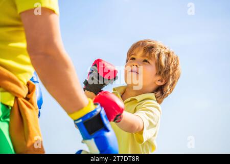 Vater trainiert seinen Sohn beim Boxen. Mann - Großvater Kind Junge, der in Boxstellung steht. Kämpfer. Mann, der Boxen trainiert, kleiner Junge in roten Boxhandschuhen Stockfoto