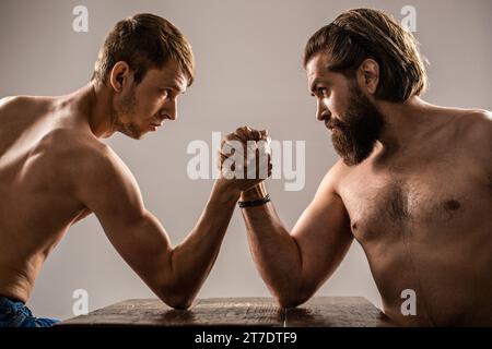Zwei Mannshände schlossen den Arm, stark und schwach, ungleich. Armringen. Arme mit dünner Hand, großer, starker Arm im Studio Stockfoto