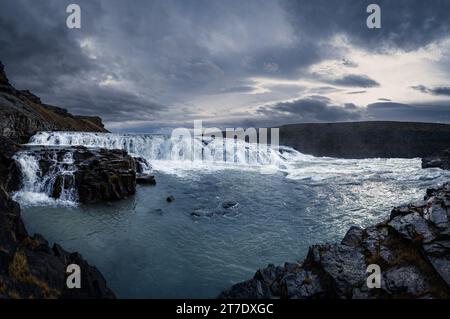 Ein majestätischer Wasserfall, der von einem ätherischen Hintergrund aus weichen weißen Wolken herabstürzt, vor den ruhigen Blautönen eines Ozeans Stockfoto