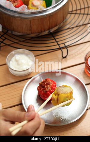 Weibliche asiatische Hand essen Siew Mai mit Essstäbchen, chinesisches Dimsum-Dumpling Stockfoto