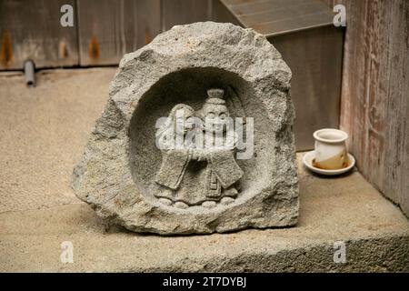 In Stein gehauene Dosojin, japanische Statue mit einem Paar, das das Vorderhaus in der Stadt Shukunegi auf Sado auf der Insel dekoriert. Stockfoto