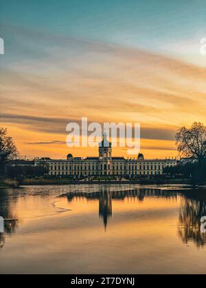 Eine ruhige Landschaft mit einem See mit einem Spiegelbild eines hohen Gebäudes, umgeben von üppigen Bäumen im Vordergrund Stockfoto