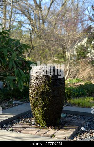 Ein Brunnen, umgeben von einem malerischen Steinweg, gesäumt von Bäumen Stockfoto