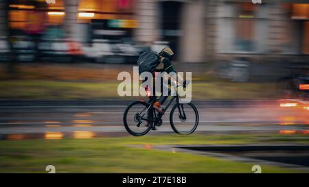 Ein Mann in einem Taucheranzug, der auf einer Straße mit dem Mountainbike fährt Stockfoto