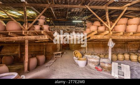 Eine Auswahl an Töpfen und Krügen aus Ton, die auf Regalen in einer rustikalen Werkstatt ausgestellt sind Stockfoto