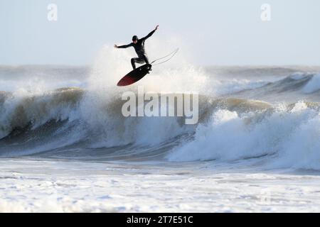 Surfaktion auf dem Gower. Surfer wird in Sprühsprüngen hervorgehoben, ohne die brechende Welle zu überspringen Stockfoto