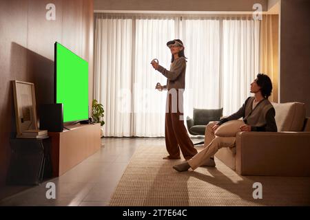 Die Menschen schauen und genießen neben dem Fernseher, Monitor mit grünem Bildschirm Stockfoto