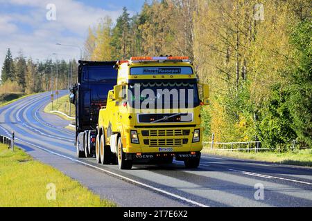 Gelbes Volvo FH Hochleistungs-Bergungsfahrzeug von Hinaus Raasepori, das im Herbst einen Sattelschlepper entlang der Autobahn zieht. Raasepori, Finnland. Oktober 2023. Stockfoto