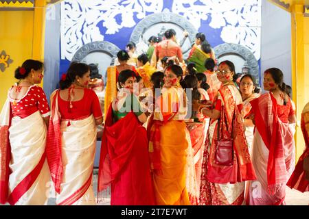 Birbhum, Westbengalen, Indien - 24. Oktober 2023: Schöne bengalische Frauen in traditioneller Kleidung mit roten, lächelnden Gesichtern, die während des letzten Tages zurückblicken Stockfoto