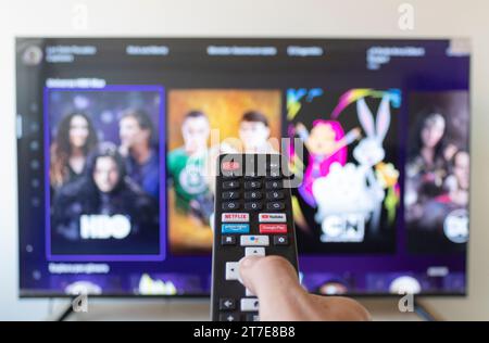 Nahaufnahme mit einem männlichen rechten Hand, der eine schwarze Smart tv-Fernbedienung hält und in der HBO MAX-Streaming-App sucht Stockfoto