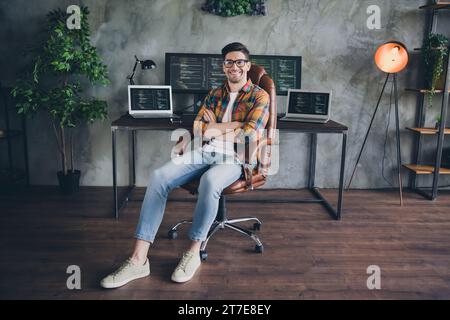 Großes Porträt des positiven Hardware-Experten Guy sitzender Stuhl überkreuzte Arme Arbeitsplatz Netbook pc Display Schreibtisch drinnen Stockfoto