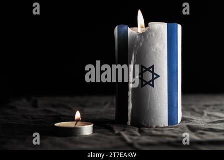 Brennende Kerze mit Israel-Flagge auf schwarzem Hintergrund. Kriegskonzept. Holocaust-Gedenktag. Nationale Trauer. Stockfoto