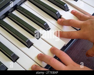 Eine Nahaufnahme eines Handpaares, das auf einer Klaviertastatur mit mehreren schwarzen und weißen Tasten spielt Stockfoto