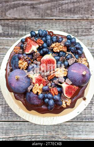 Köstlicher Vanillekäsekuchen mit geschmolzener Zartbitterschokolade, Feigen, Trauben, Pekannüssen auf der Oberseite. Ernte Herbstdekoration Stockfoto