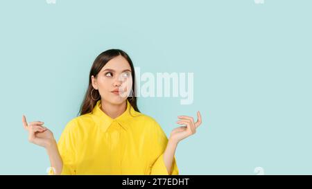 Verwirrte junge Dame, die auf Kopierraum und Gesten blickt Stockfoto