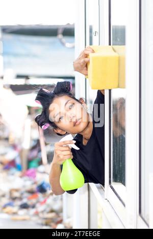 Eine junge Frau wäscht die Außenfenster in einem Wohnhaus Stockfoto