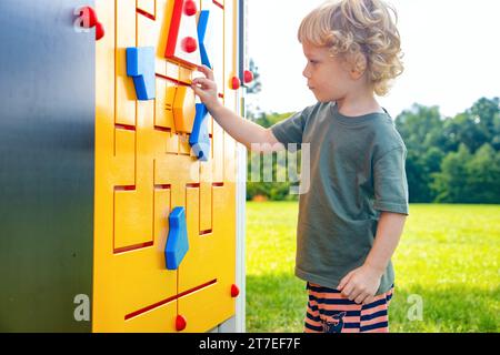 Der kleine Junge erkundet den Außenbus auf dem Spielplatz Stockfoto