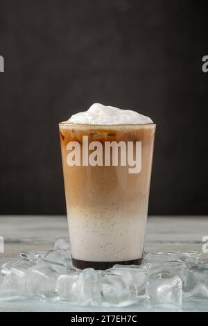 Mehrschichtiger Eiskaffee-Latte in Glasbecher auf Holztisch Stockfoto