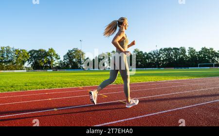 Seitenansicht einer Frau, die im Sonnenlicht auf einer Schiene läuft Stockfoto