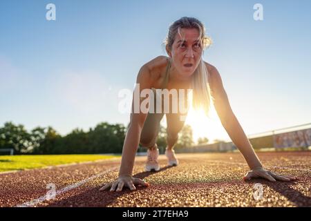 Entschlossene Athletin in Startposition auf der Laufbahn Stockfoto