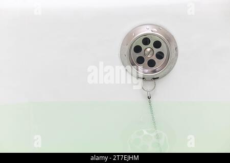 Badewanne mit Wasserabflussöffnung. Ablauföffnung in der Badewanne. Bad mit Wasser Stockfoto