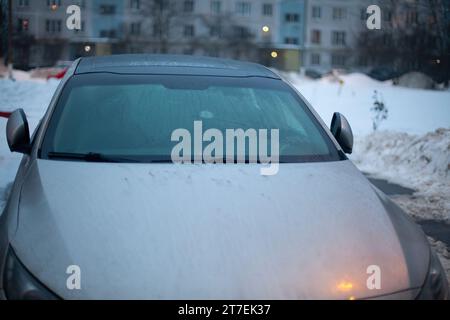 Das Auto steht im Winter auf dem Parkplatz. Das Auto steht im Schnee. Winterparkplätze in der Stadt. Viel Schnee auf der Straße und auf den Transportmitteln. Stockfoto