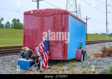 NEW ORLEANS, LA, USA - 11. NOVEMBER 2023: Gemalter Wohnwagen mit amerikanischer Flagge und anderen Objekten neben Eisenbahngleisen in Uptown Stockfoto