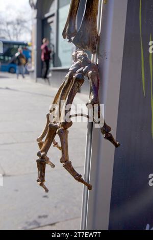 Nahaufnahme einer knochigen Skeletthand mit Leuten auf der Straße im Hintergrund. Stockfoto