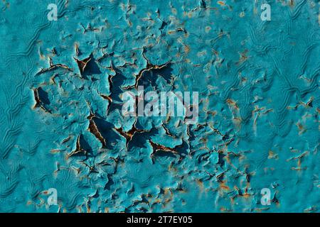 Die Farbe blättert blau an der Wand ab. Alte Betonwand mit rissiger abblätternder Farbe. Verwitterte, rauh lackierte Oberfläche mit Rissen- und Abschälungsmustern. Hig Stockfoto