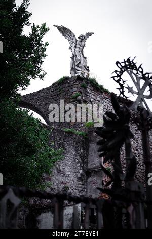Guardian Serenity: Vertikale Ansicht der Engelskulptur auf der Comillas Cemetery Wall, Kantabrien, Spanien Stockfoto
