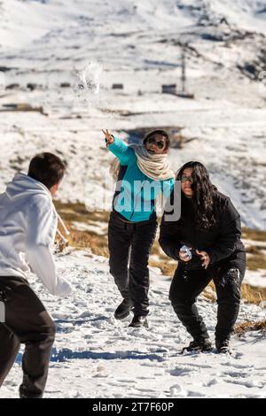 Die Latino-Familie genießt einen verspielten Schneeballkampf inmitten der atemberaubenden verschneiten Landschaft der Sierra Nevada, Granada Stockfoto