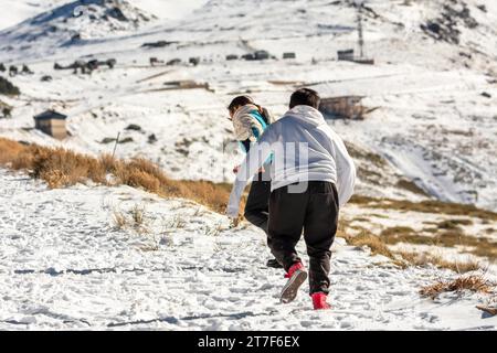 Lateinische Mutter und Sohn laufen im Schnee Stockfoto