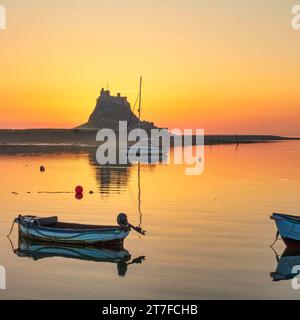 Sonnenaufgang im Sommer über dem Schloss Lindisfarne auf der Heiligen Insel Lindisfarne in Northumberland, vom Hafen aus gesehen Stockfoto